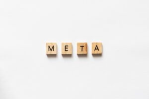 META spelled out with wooden letter tiles on white surface.
