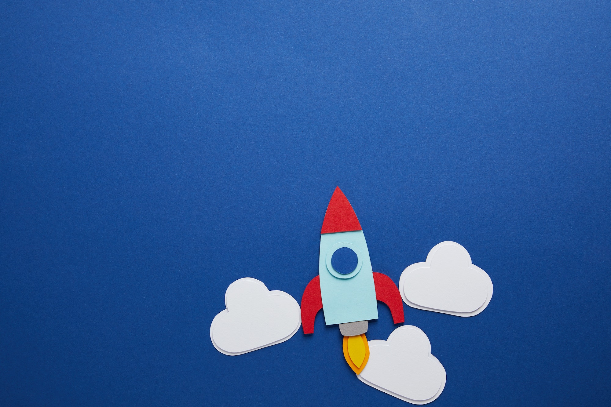 clouds and rocket on blue background with copy space