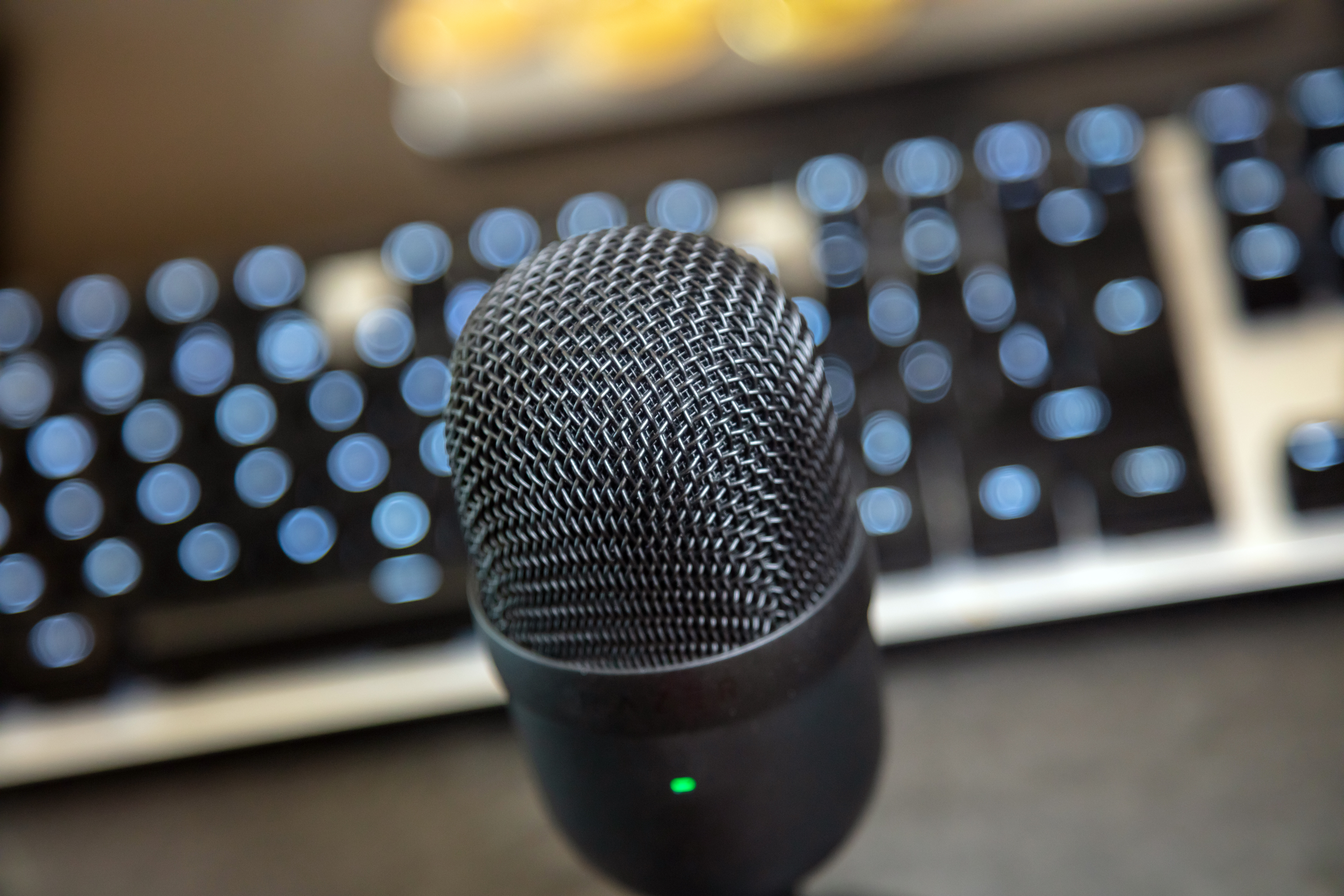 Microphone condenser black metallic, blur keypad and monitor background.
