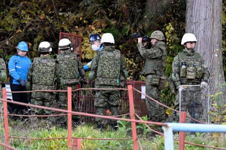 自衛隊のクマ対策現場。箱わなを運ぶ隊員たちの様子が、安全対策の徹底を示しています。(出典: 沖縄タイムス, CC BY 4.0)